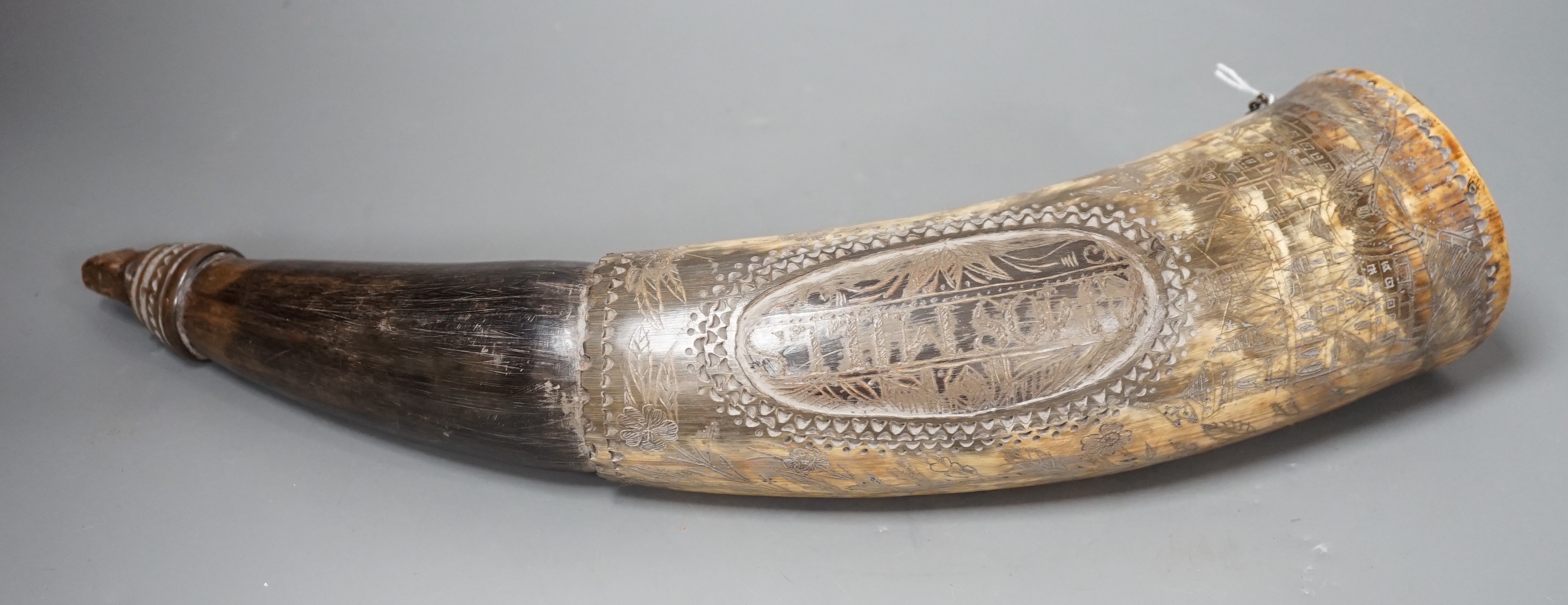 An early 19th century scrimshaw powder horn, ornately engraved with the Royal Coat of Arms, a castle and galleon and an inscription: Amos Mills. 38cms long.